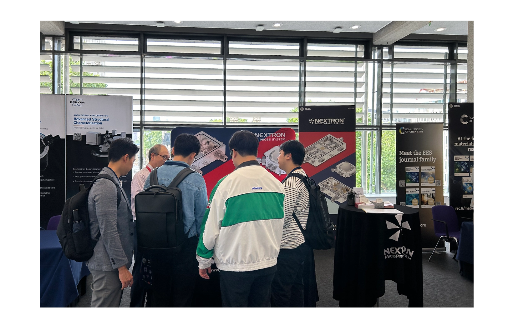 The branch manager of Nextron is explaining the product to several customers. The customers are listening to the branch manager.